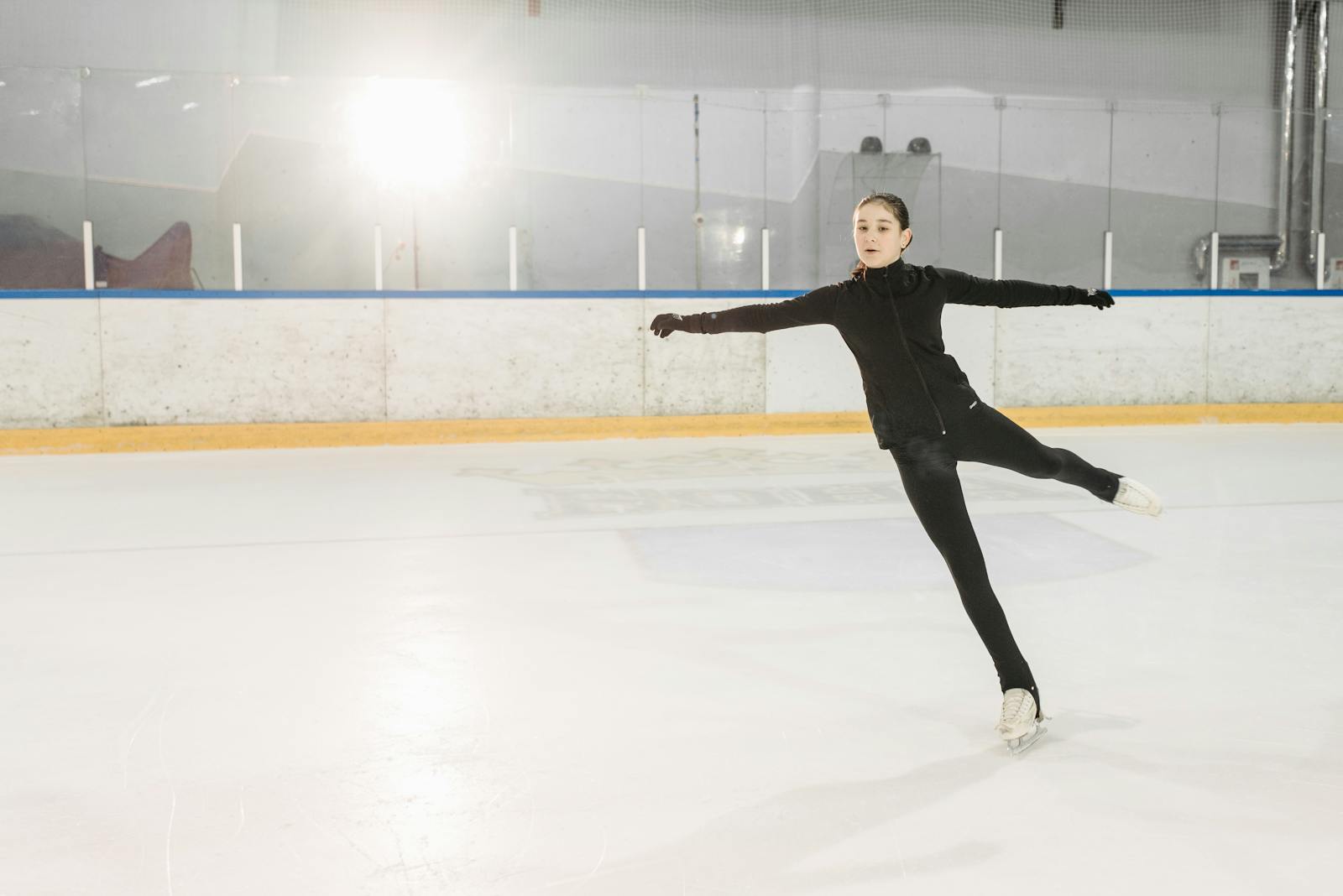 Une jeune femme glisse gracieusement sur des patins à glace dans une patinoire intérieure. Capture du mouvement et de l'élégance.