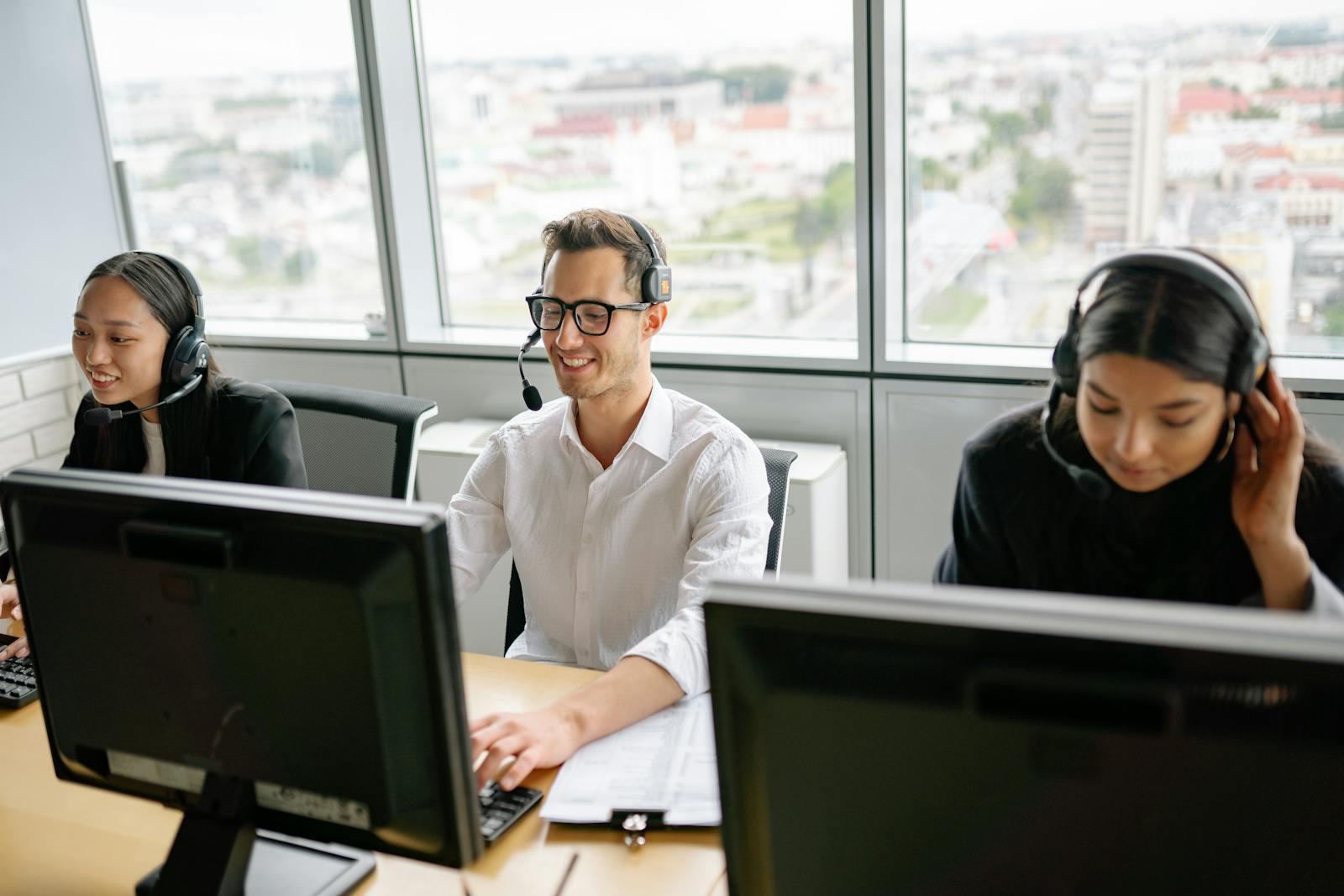 Groupe d'employés du centre d'appels portant des casques, collaborant dans un environnement de bureau lumineux.