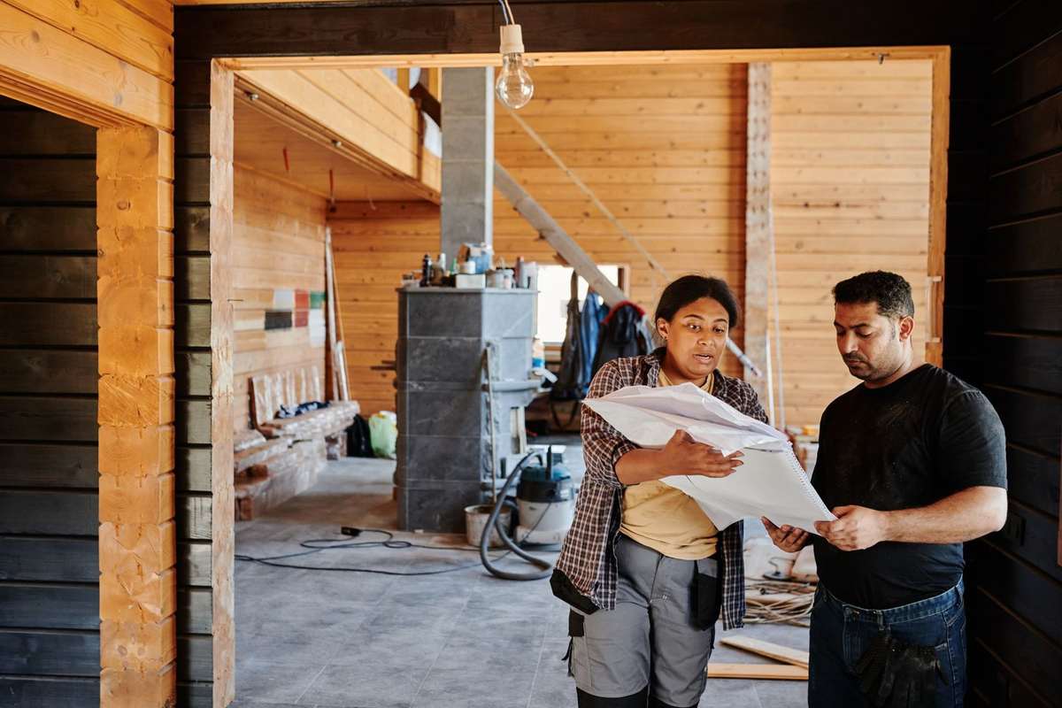 Deux individus consultent des documents dans un cadre de construction en bois
